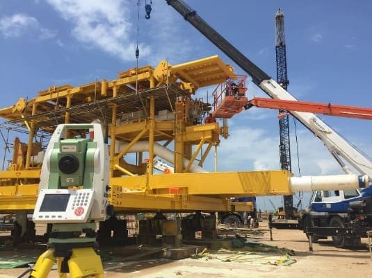 Total station set up at a fabrication yard with cranes in the background